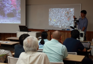 （写真）2016年7月9日，公開研究発表会「えっ！但馬に大学院があったの？」，顕微鏡を使って岩石薄片の観察